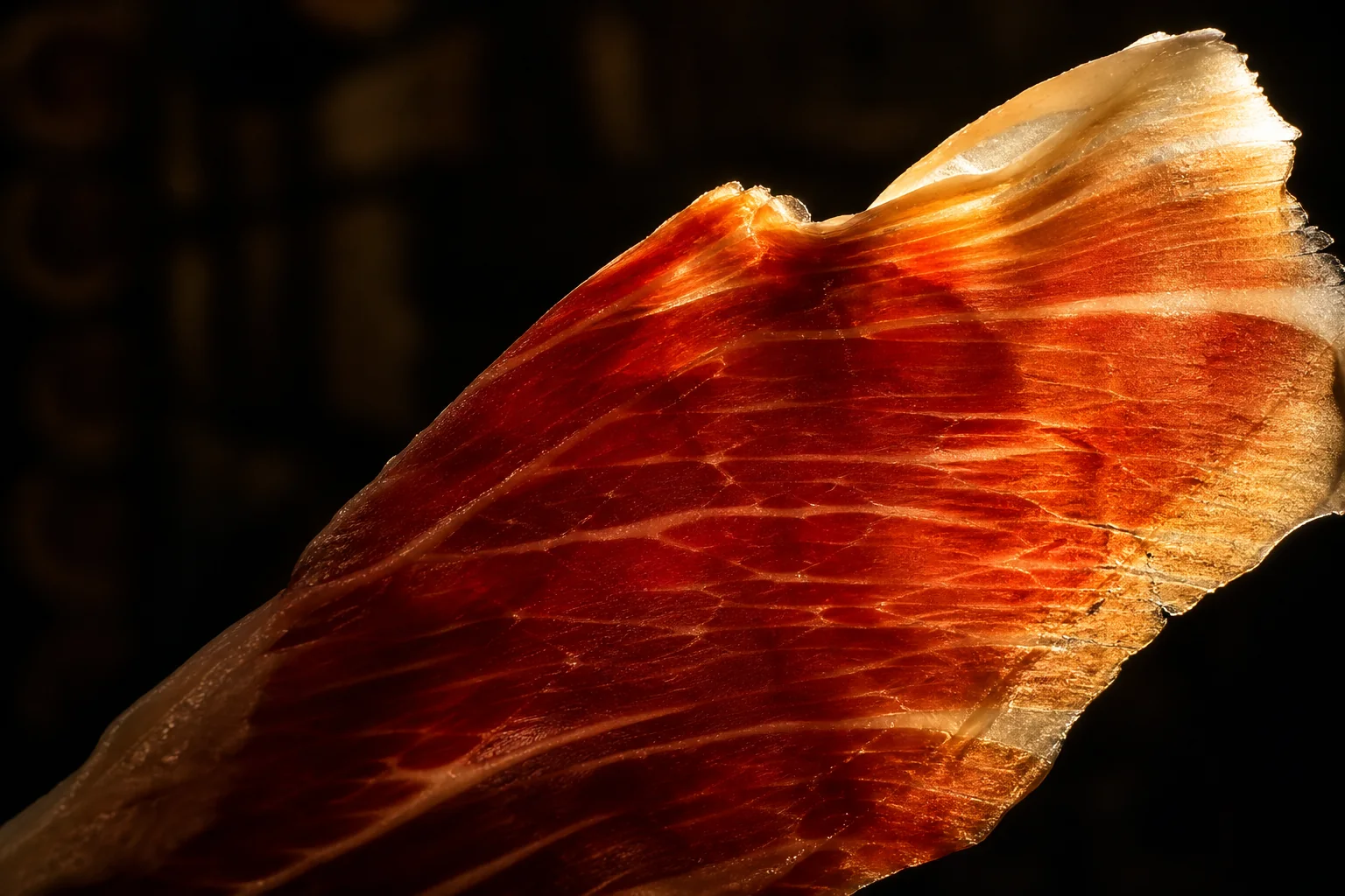 Loncha fina de jamón serrano sobre fondo oscuro
